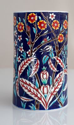 a blue vase with flowers and birds painted on the outside, sitting on a white surface