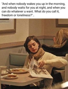 a woman sitting at a table with food in front of her and reading a newspaper