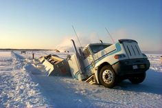 a truck that is sitting in the snow with it's front end flipped over