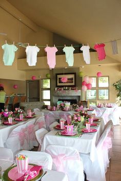 a baby shower party with pink and green decorations on the ceiling, table cloths draped over tables