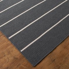 a gray rug with white stripes on it sitting on a wooden floor next to a wood floor