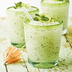 two glasses filled with green drinks on top of a table