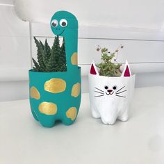 two planters with plants in them sitting on a white table next to each other