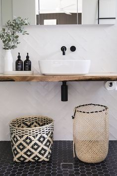 a bathroom with black and white flooring and a wooden shelf holding two baskets on it