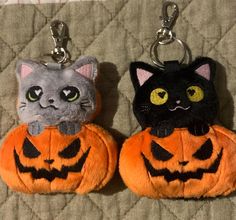 two key chains with cats on them sitting next to each other in front of a quilt