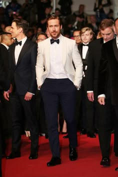 a man in a tuxedo walks down the red carpet