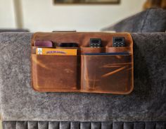 a cell phone holder is attached to the back of a couch with two phones in it