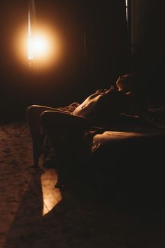 a person laying on a couch in the dark with a light shining down on them