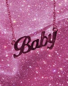 a necklace with the word baby hanging from it's center on a pink background