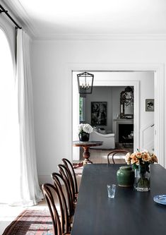 a dining room table with chairs and vases on it in front of an open door