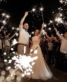 a newly married couple holding sparklers in the air