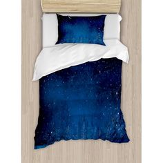 a bed with a blue and white comforter on top of it next to a wooden headboard