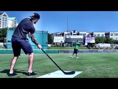 a man hitting a ball with a golf club on the grass in front of buildings