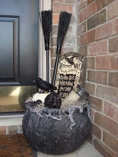 a halloween decoration with brooms and other items sitting in a pot on the front porch