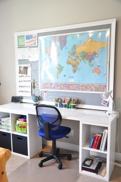 a child's desk with a map on the wall above it and toy bins below