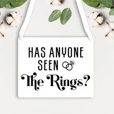 a white sign that says has anyone seen the rings? next to some cotton flowers