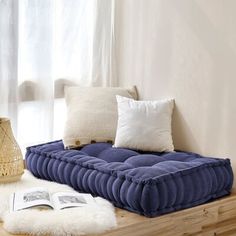 a couch that is on top of a wooden table with pillows and a book in front of it