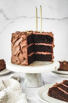 there is a chocolate cake with two candles on it and one slice has been cut