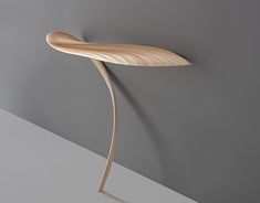 a curved wooden object on a gray wall