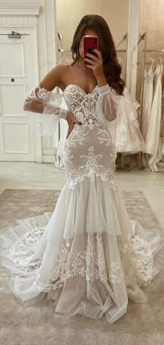 a woman taking a selfie while wearing a wedding dress in front of a mirror