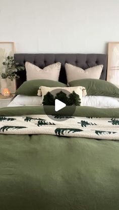 a bed with green comforter and pillows on it, next to two framed pictures