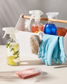 cleaning supplies in a container with gloves and soap on the table next to each other