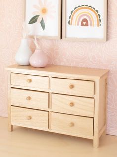 there are two pictures on the wall next to a dresser with drawers and vases