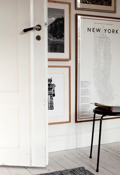 an open door in a white room with pictures on the wall and a black chair