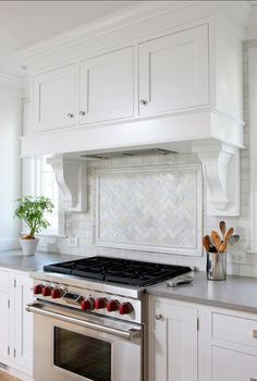 a stove top oven sitting inside of a kitchen next to white cabinets and counter tops