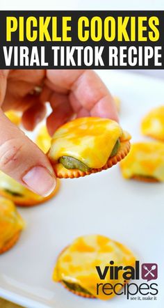 a hand holding a pickle cookie over a white plate with other small cookies in the background