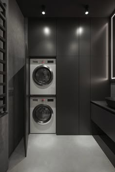 a washer and dryer in a room with dark colored walls, flooring and lighting