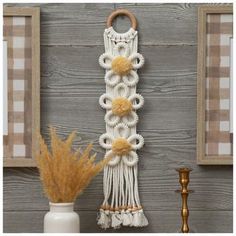 the wall hanging is decorated with flowers and tassels, along with a potted plant