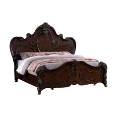 an ornate wooden bed frame with white sheets and pink comforter on the headboard