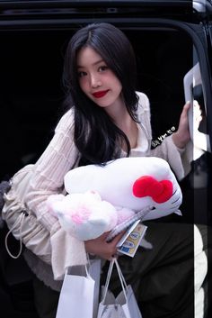 a woman holding a hello kitty stuffed animal in her hand while sitting in the back of a car