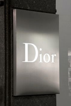 a metal sign that reads dior on the side of a black and silver building