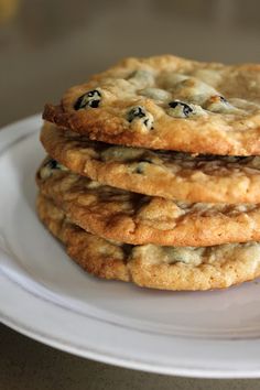 three cookies stacked on top of each other on a white plate with blueberries in the middle