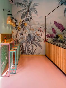 the wallpaper in this restaurant is painted with tropical flowers and palm trees, along with colorful stools