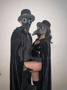 two people dressed up in costumes and masks, one wearing a black mask while the other wears