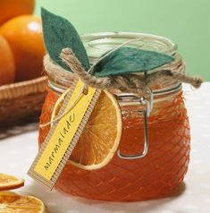 a jar filled with oranges sitting on top of a table next to sliced oranges