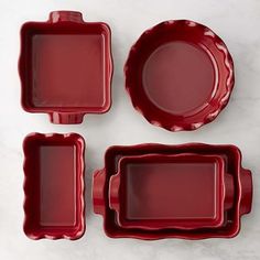 three red dishes and two plates on a white surface