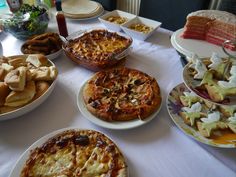 a table topped with lots of different types of pizzas and other food on plates