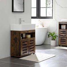 a white bath tub sitting next to a wooden cabinet in a bathroom under a window