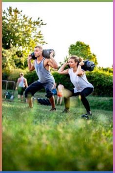 two people are doing exercises in the grass with boxing gloves on their hands and one is holding a punching bag