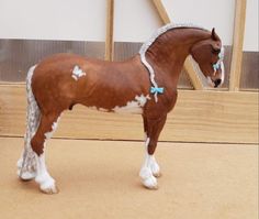 a brown and white horse standing on top of a wooden floor