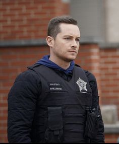 a police officer standing in front of a brick building