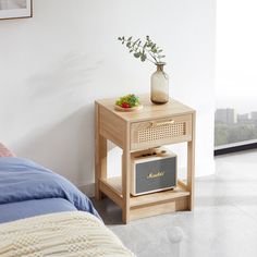 a small wooden table with a radio on it next to a bed and a plant