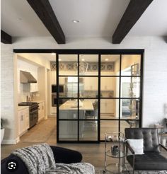 a living room filled with furniture and a large glass door that leads to an open kitchen