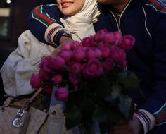 a man and woman sitting next to each other with flowers in front of their faces