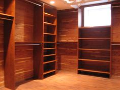 an empty walk in closet with wooden shelves and lights on the ceiling above it is a chandelier