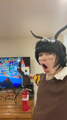 a person with horns on their head is holding something in front of the camera while wearing a costume